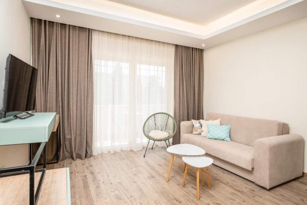 Una sala de estar moderna con un escritorio azul claro, un sofá beige, una silla verde y una mesa de centro blanca.