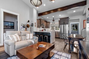 A modern kitchen with a central island, bar stools, and a dining table.