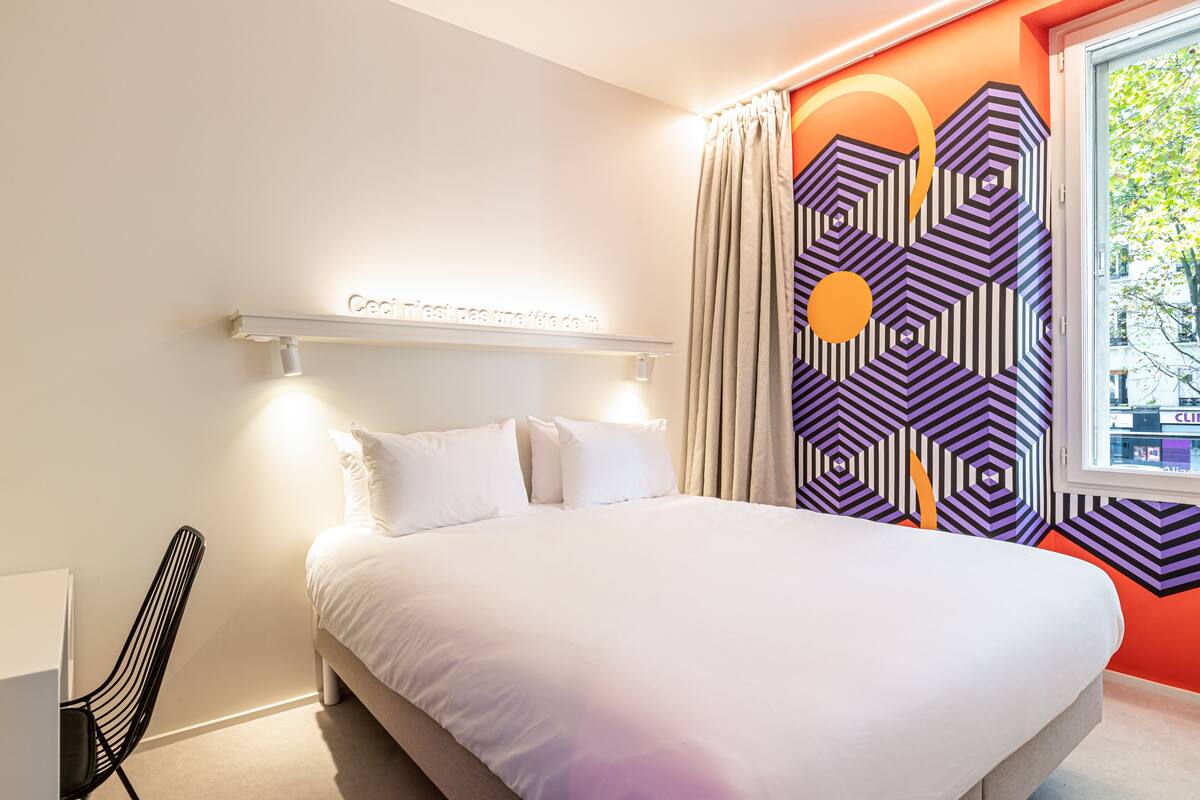 Une chambre d’hôtel moderne avec un grand lit, un bureau et une vue sur la ville.
