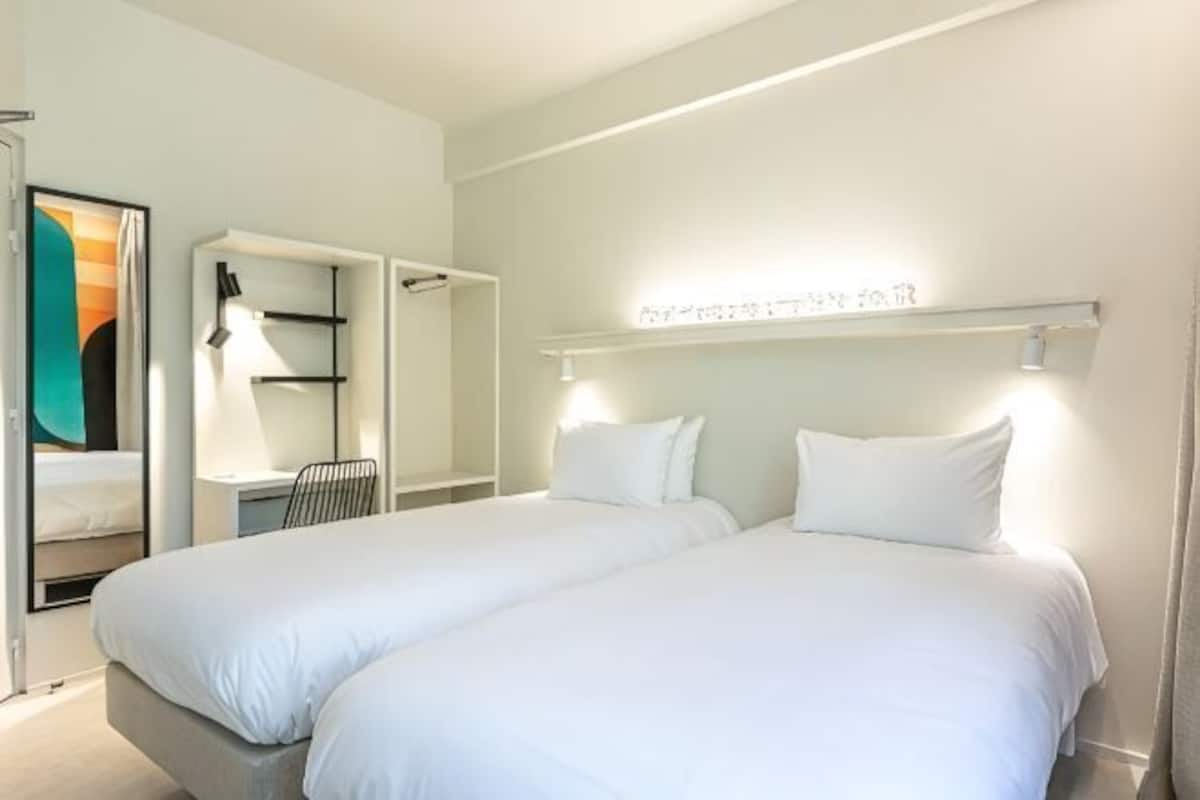 Une chambre dâhĂŽtel avec deux lits, un bureau et une chaise.