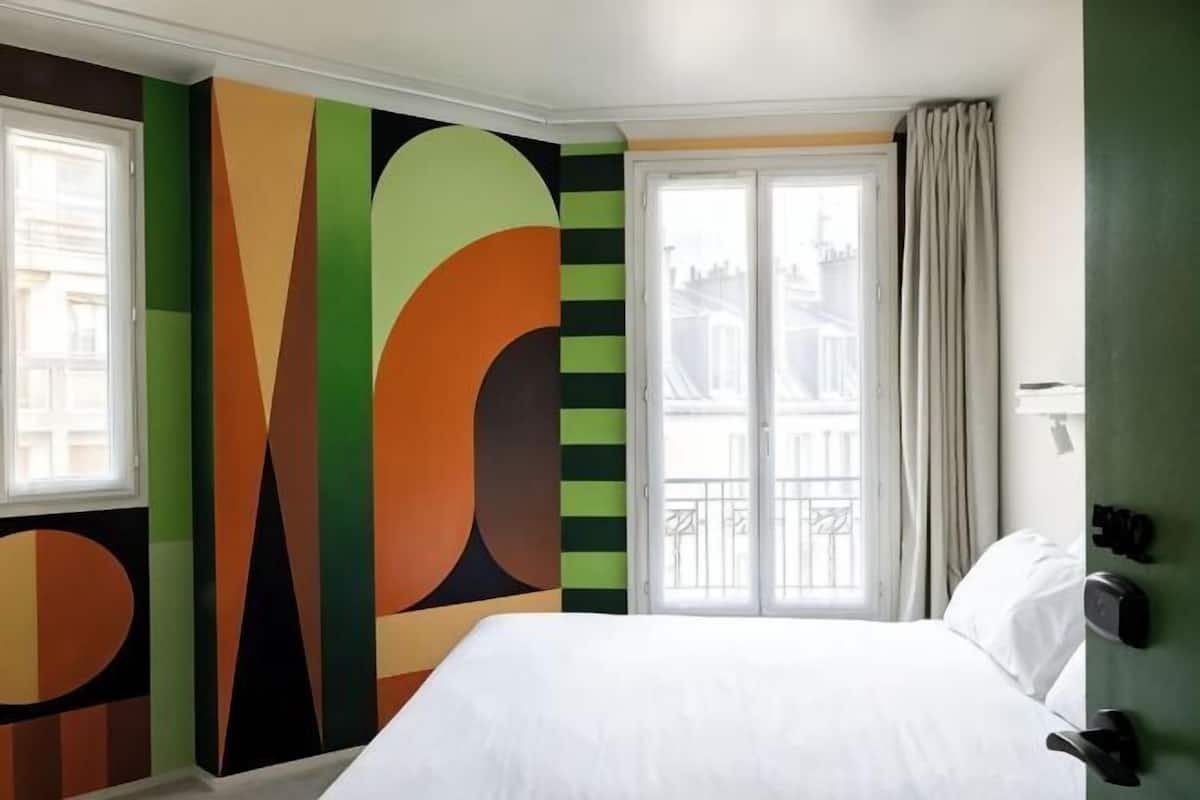 Une chambre d’hôtel avec un grand lit, une fenêtre avec des rideaux et une vue sur l’extérieur.