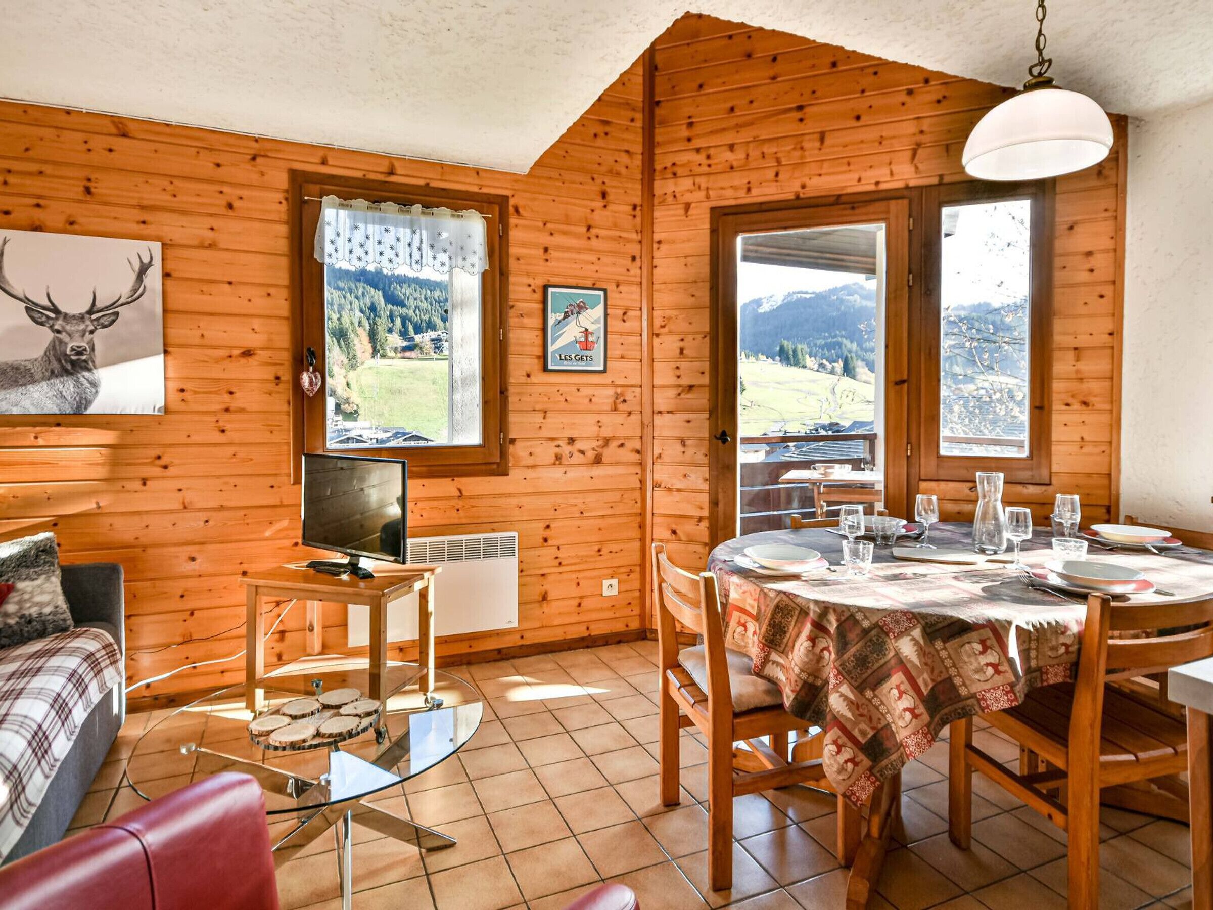 A cozy wooden cabin with a dining area, a television, and a scenic mountain view.
