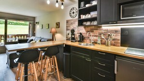 A modern kitchen with a wooden island, black cabinets, and a built-in microwave. - Renovated Studio with Cabin in Village Center, Near Ski Lifts - Les Gets (Les Gets)