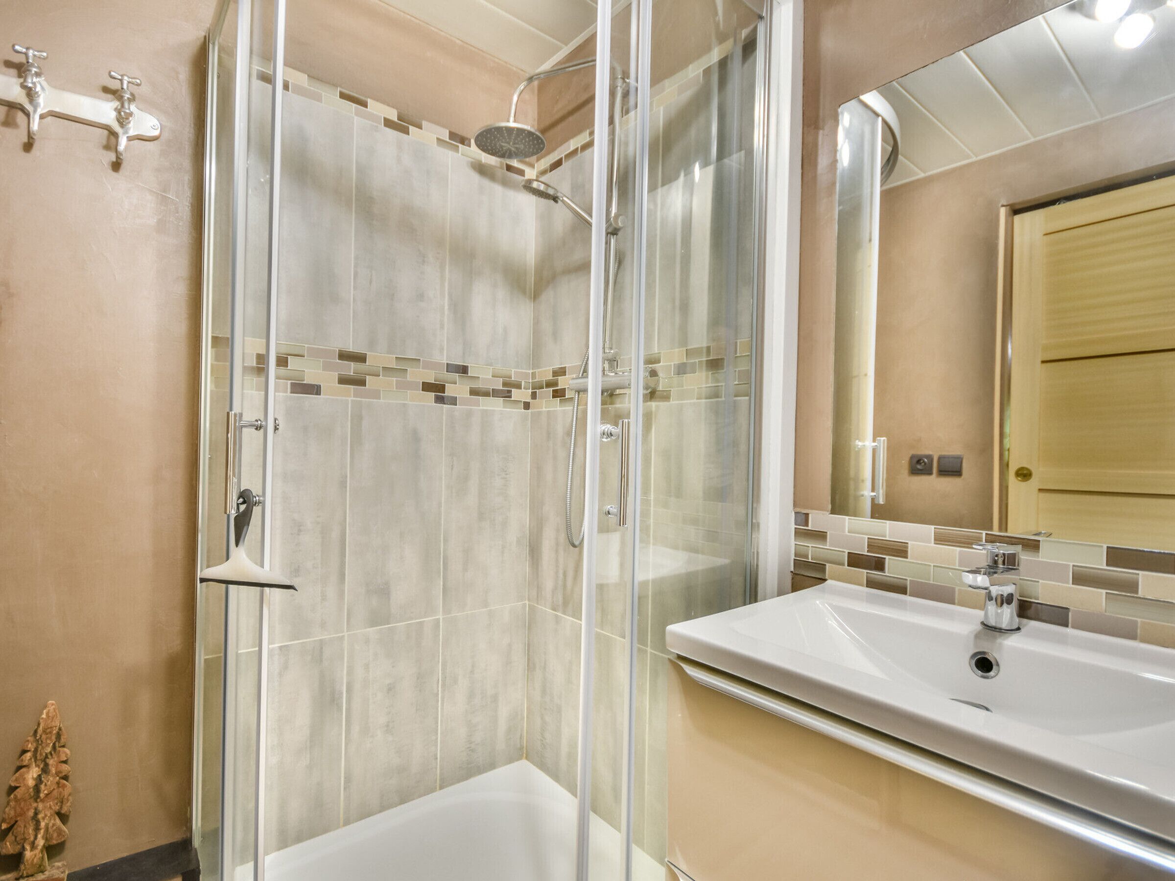Une salle de bain moderne avec une douche à parois de verre, un lavabo blanc et un miroir au-dessus.