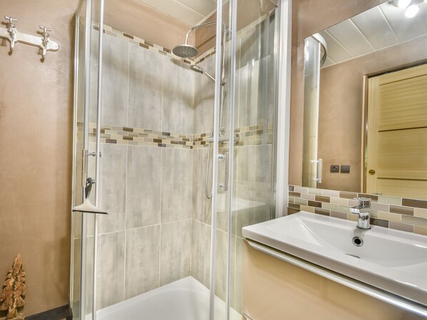 Une salle de bain moderne avec une douche à parois de verre, un lavabo blanc et un miroir au-dessus.