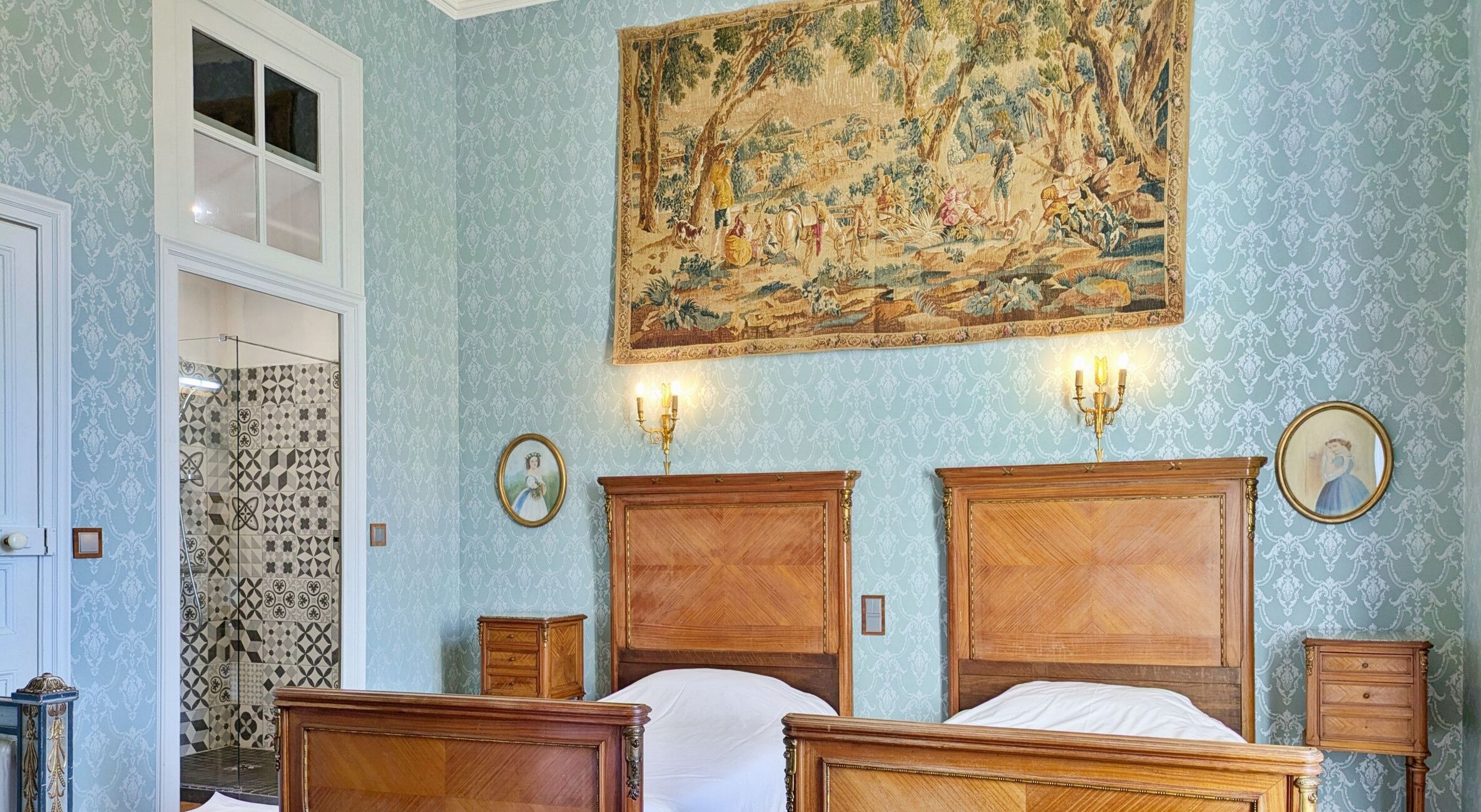 Ein Schlafzimmer mit zwei Holzbett, einer großen Wandteppich und einer Duschkabine mit Muster.