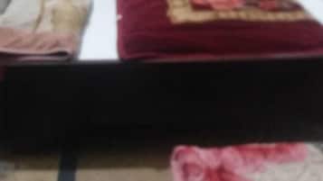A bed with a white headboard, a red and gold blanket, and a floral-patterned bedspread.