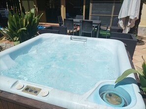 Ein Whirlpool mit Bedienfeld, umgeben von Gartenmöbeln und Pflanzen.