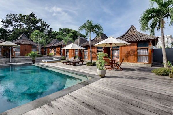 Una piscina al aire libre, sombrillas, sillones reclinables de piscina