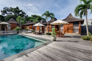 Una piscina al aire libre, sombrillas, sillones reclinables de piscina