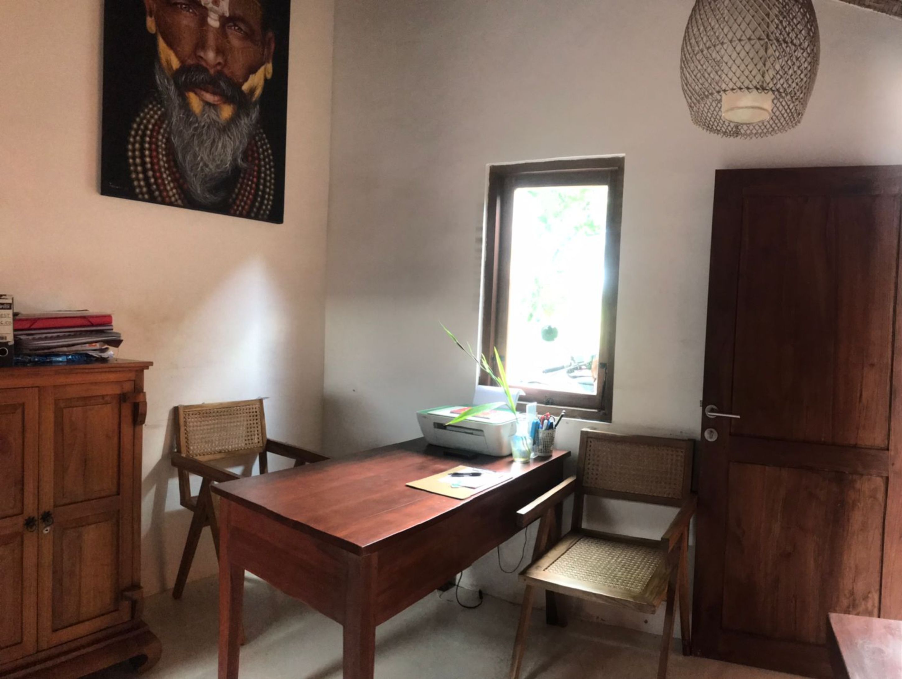 A dining area with a wooden table, two chairs, a cabinet, and a window with natural light.