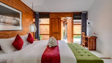 A hotel room with a large bed, a green ottoman, a wooden desk, and a view of the outdoors.