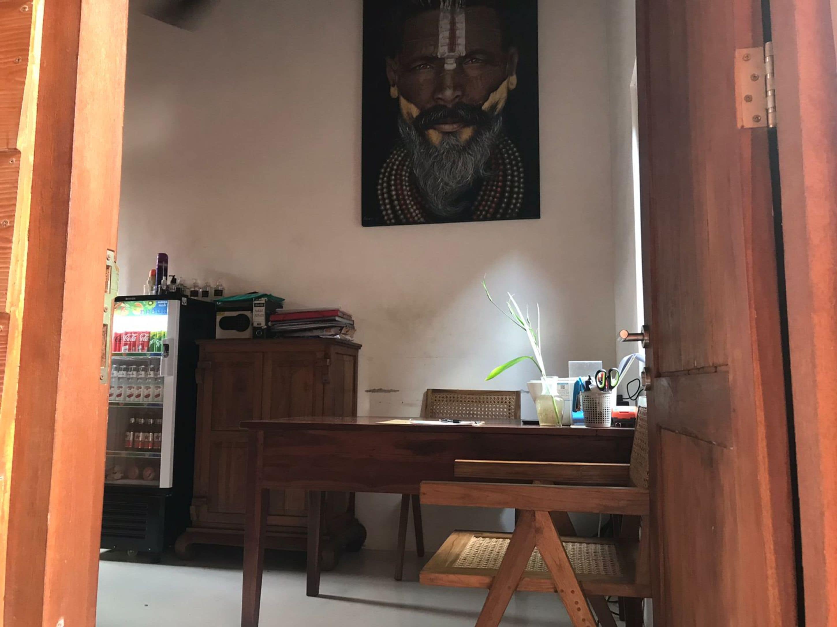 A wooden dining table with chairs, a wooden cabinet, a wall-mounted painting, and a vending machine.