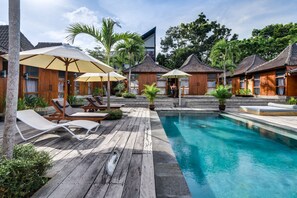 Una piscina al aire libre, sombrillas, sillones reclinables de piscina