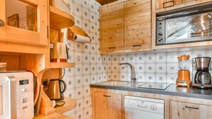 A compact kitchen with wooden cabinets, a built-in microwave, a coffee maker, and a dishwasher. - Paméo 1 - Cozy 6-Person Duplex Near Ski Slopes in La Turche, Les Gets (Les Gets)