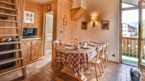 A wooden interior with a dining table set for four, a TV, and a ladder. - Paméo 1 - Cozy 6-Person Duplex Near Ski Slopes in La Turche, Les Gets (Les Gets)