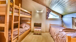 A cozy attic bedroom with wooden bunk beds, a small desk, and a window with a view. - Paméo 1 - Cozy 6-Person Duplex Near Ski Slopes in La Turche, Les Gets (Les Gets)