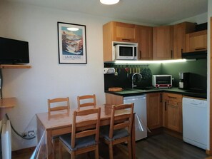 Enjoy meals at the dining table with four chairs, accompanied by a framed picture.
