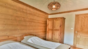 Een houten kamer met twee bedden, een garderobe en een hanglamp.