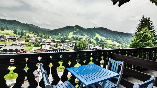 A balcony with a table and chairs overlooking a town and mountains. - Duplex T3 in Les Gets - 5 pers, panoramic view, balcony, parking, WiFi (Les Gets)