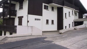 A two-story building with a white facade and dark brown roof. There is a sign on the front that reads "L'ARC EN CIEL". - Duplex T3 in Les Gets - 5 pers, panoramic view, balcony, parking, WiFi (Les Gets)