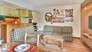 A compact living space with a kitchenette, two plaid sofas, a coffee table, and a TV. - Duplex T3 in Les Gets - 5 pers, panoramic view, balcony, parking, WiFi (Les Gets)