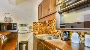 Una cocina con armarios de madera, microondas, tostadora, cafetera y salpicadero de azulejos.