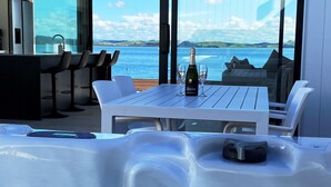 Un bain à remous avec une bouteille de champagne et des verres, offrant une vue imprenable sur un paysage aquatique.