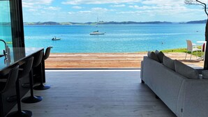 A modern kitchen with a view of the sea, a wooden deck, and a sofa.