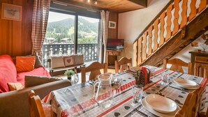 Une pièce confortable avec un coin repas, un canapé et une vue sur les montagnes.