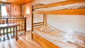 Une chambre avec un lit superposé, dotée d’un plancher et d’un plafond en bois.