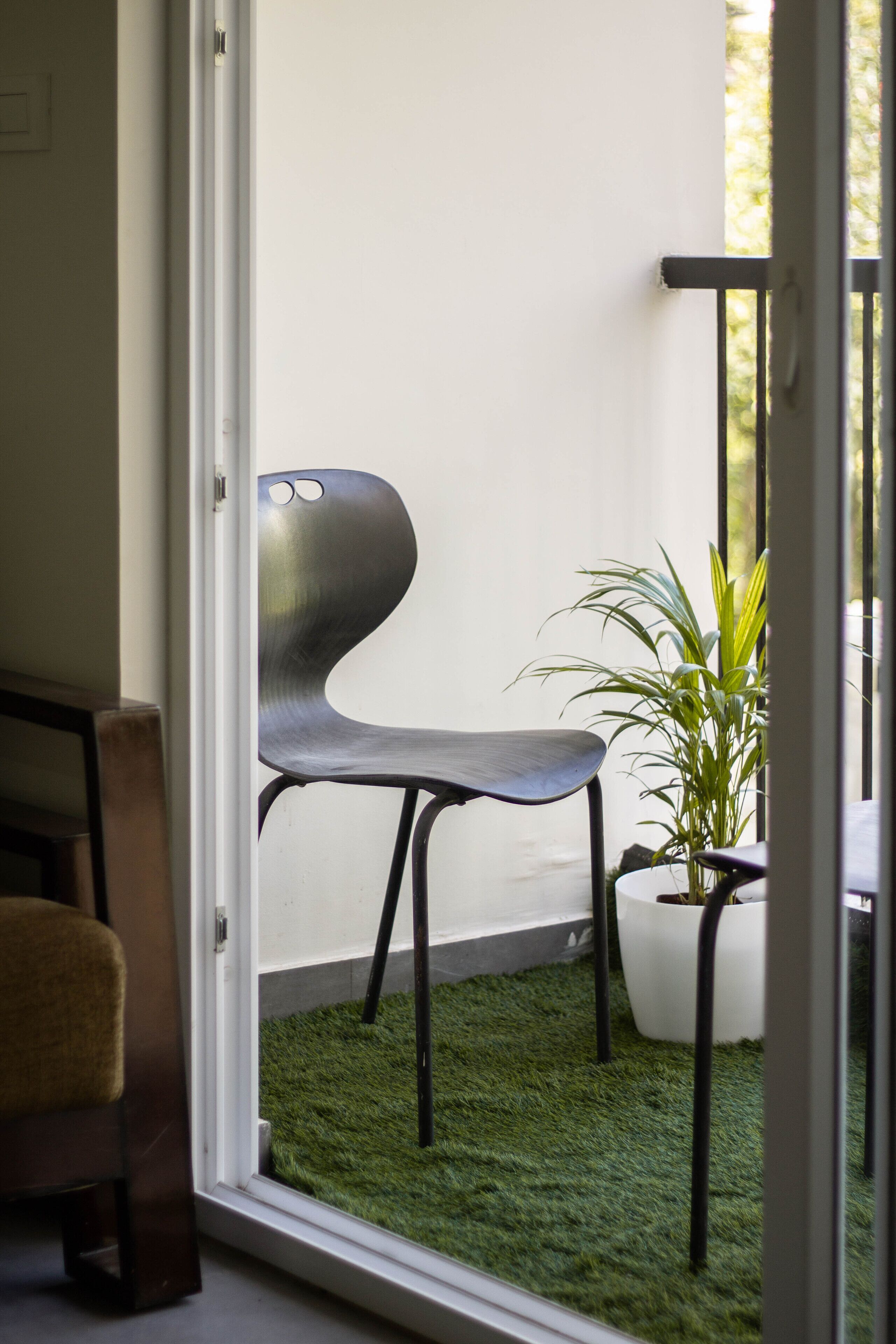 A room with a view of a balcony, a potted plant, and a modern chair.