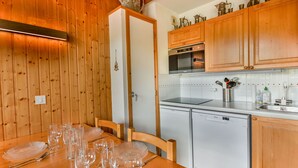 Eine Küche mit Holzvertäfelung, einem Esstisch, der für eine Mahlzeit gedeckt ist, einem Geschirrspüler und Holzschränken.