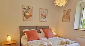 Ein Schlafzimmer mit einem Bett, zwei Kissen, einem Nachttisch mit Lampe und Wandbildern.