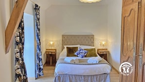 A bedroom with a bed, two bedside tables, a hanging light fixture, and a wardrobe.
