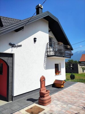 A modern house with a white exterior, a red door, and a balcony with a metal railing. - Relax Home Rajna Korenica (Plitvicka Jezera)