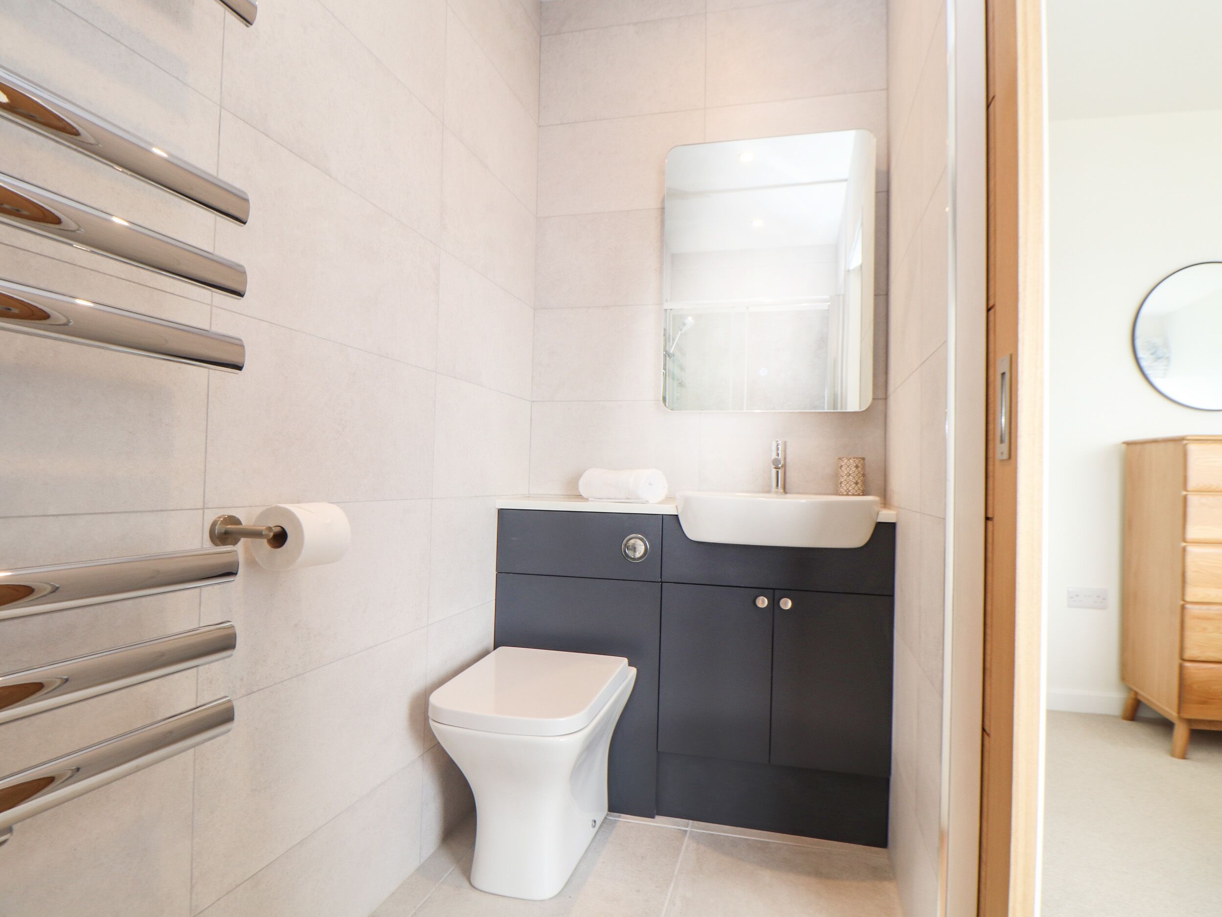 Un baño moderno con inodoro, lavamanos y toallero.
