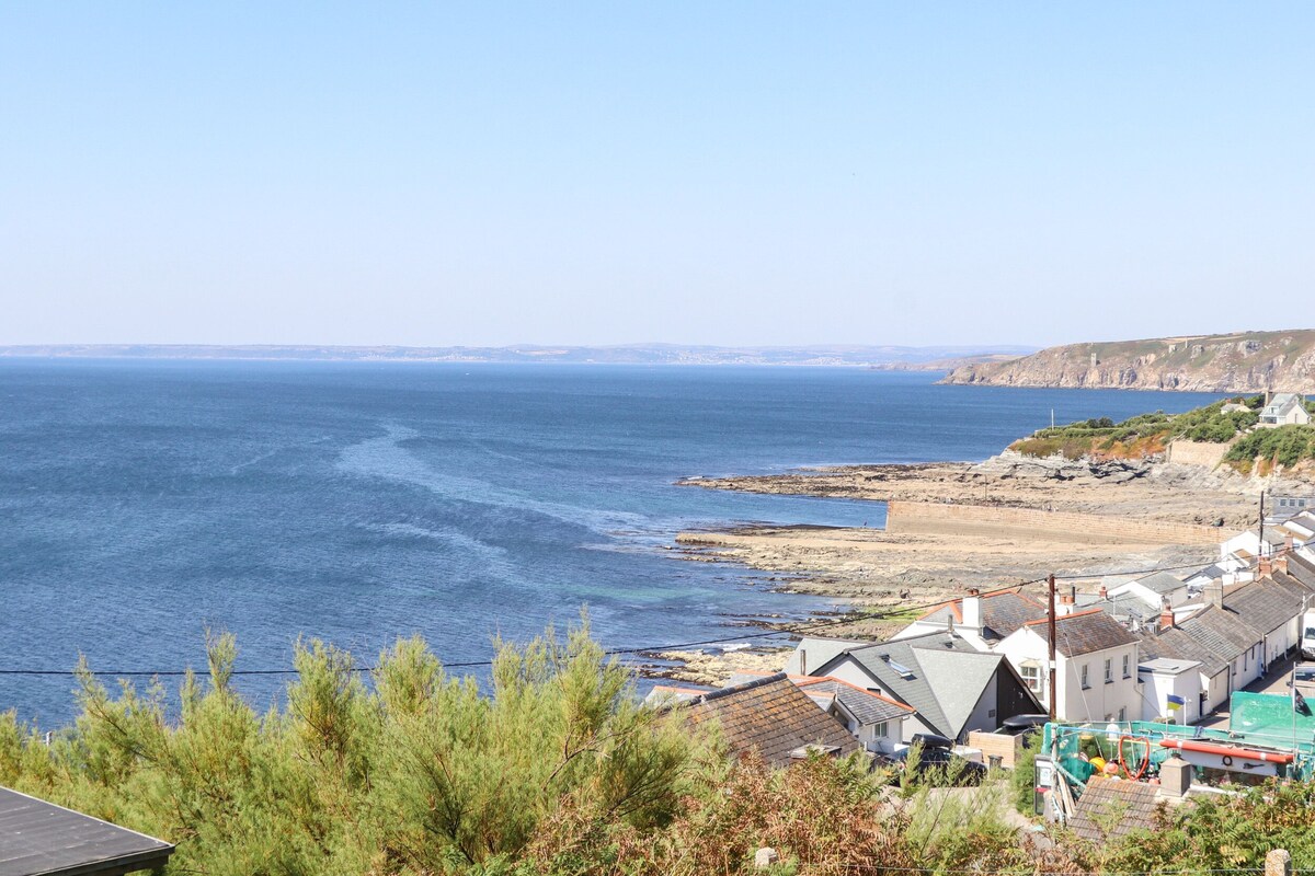 A coastal town with houses along the sea, rocky cliffs, and a clear view of the ocean.