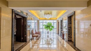 A hotel lobby with a polished floor, a chandelier, a potted plant, and a staircase. - Taishengyuan Hotel (Shuozhou)