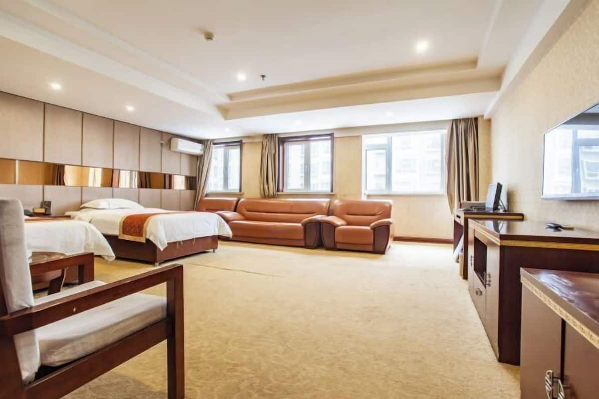 A hotel room with a bed, a sofa, a desk, and a chair.