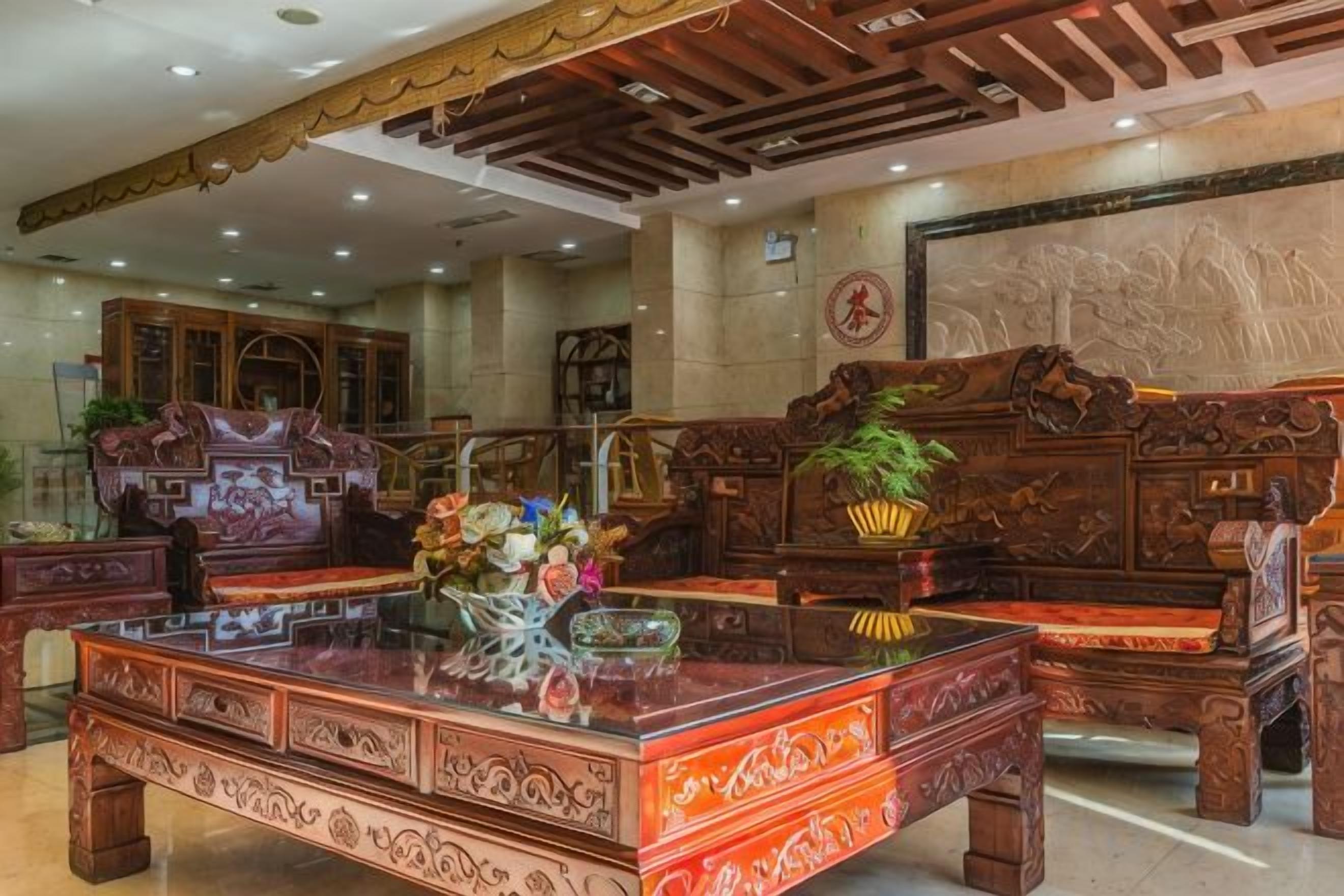 A traditional interior with ornate wooden furniture, a glass-top table with a floral arrangement, and a large mural on the wall.