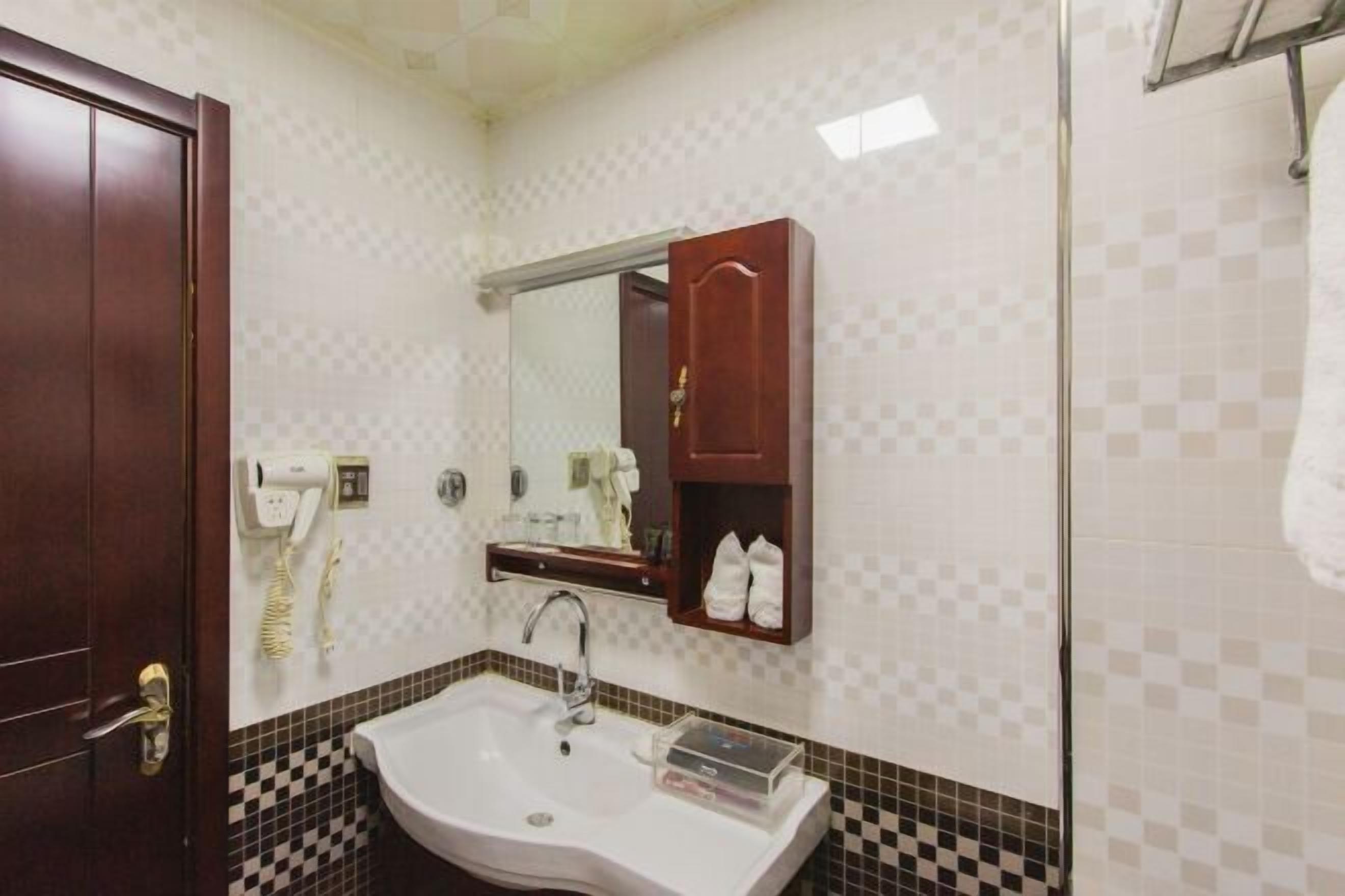 A bathroom with a white sink, a mirror, a towel rack, and a wooden cabinet.