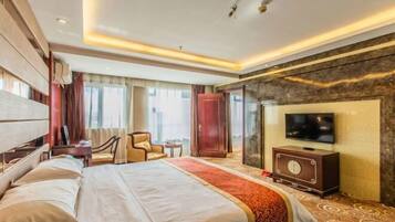 Una habitación de hotel con una cama grande, televisión, escritorio y una silla.