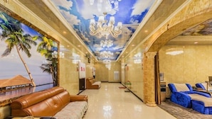 A hotel lobby with a beach mural, leather seating, a chandelier, and a blue sofa. - Taishengyuan Hotel (Shuozhou)