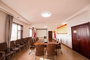 Un salón de conferencias con una larga mesa y sillas, banderas y un cartel en la pared.