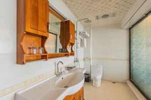 Een badkamer met een houten wastafelmeubel, een grote spiegel en een witte wasbak.