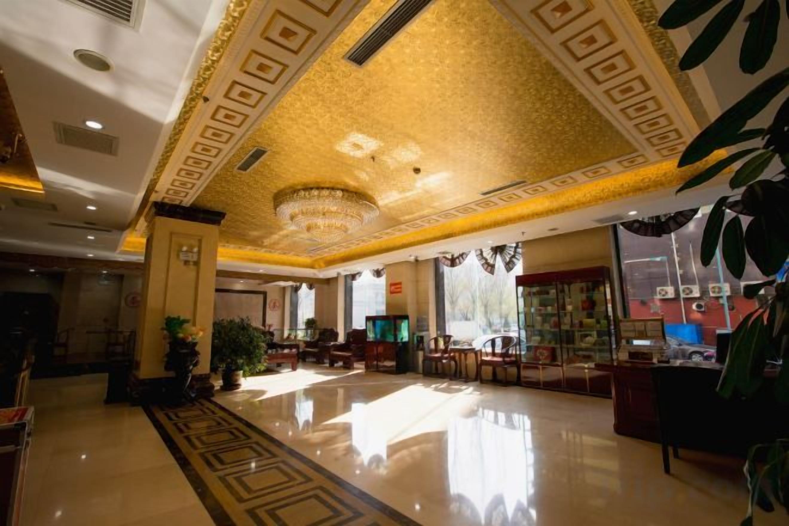A hotel lobby with a polished floor, a chandelier, and a seating area.