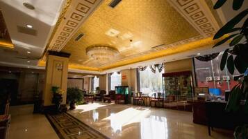 A hotel lobby with a polished floor, a chandelier, and a seating area.