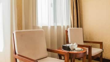 A hotel room with two wooden chairs and a small round table with a teapot and cups.