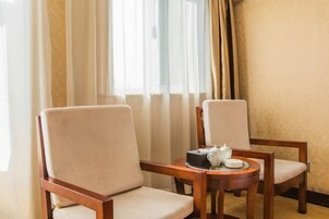 Una habitación de hotel con dos sillas de madera y una pequeña mesa redonda con una tetera y tazas.